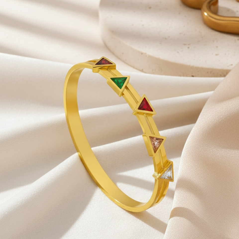 gold plated bangle for women featuring five colorful triangular American Diamond (AD) stones in red, green, purple, and clear, displayed on a minimalist gold band against a neutral stone background