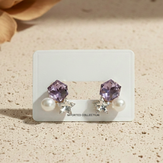 Pair of earrings on a display card with 'Imported Collection' text, set against a beige background.