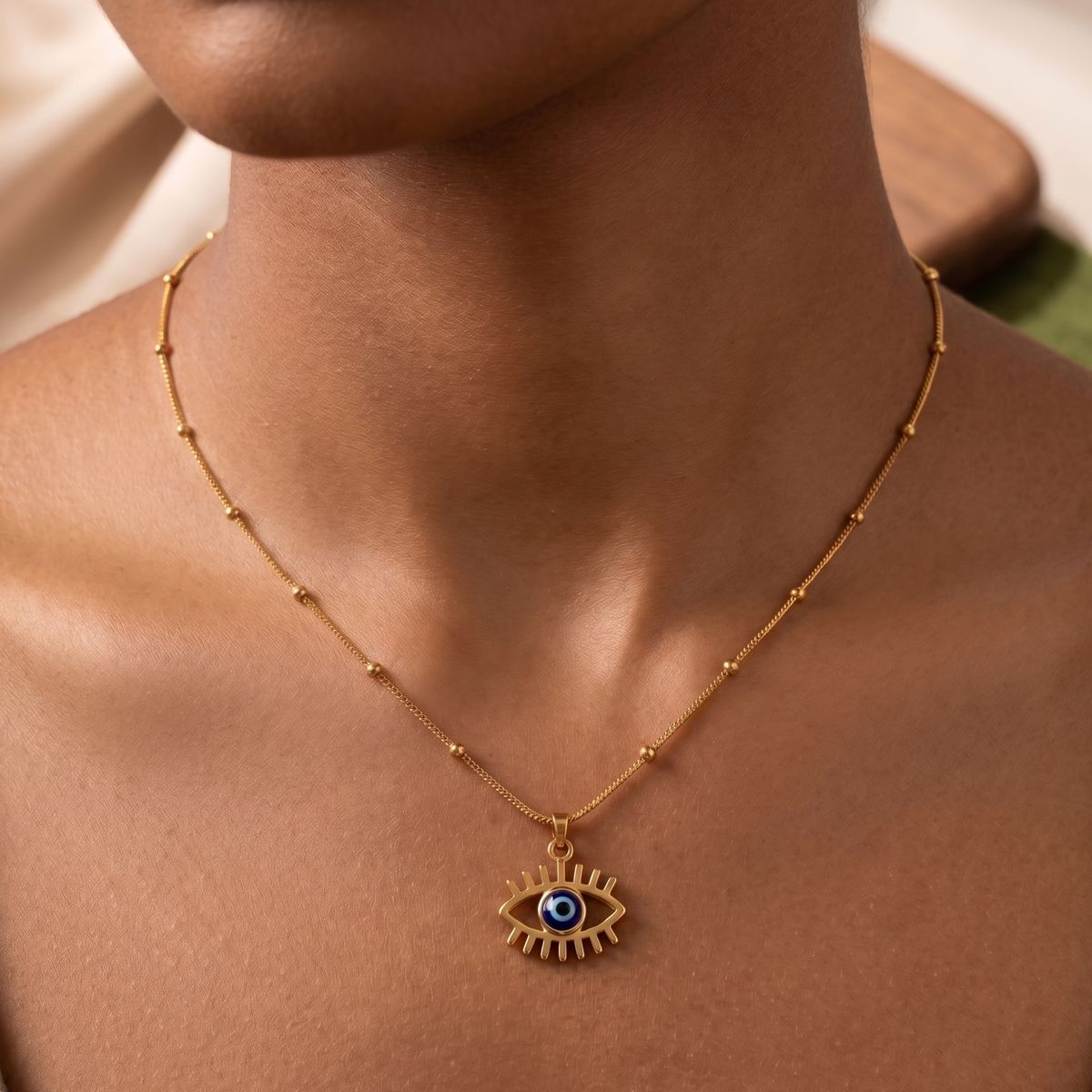 Gold necklace with an eye pendant on a person's neck