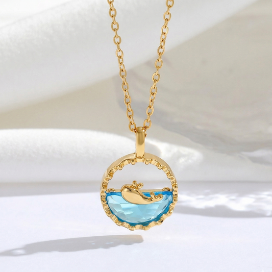 Gold necklace with a pendant featuring a whale in the ocean on a white background