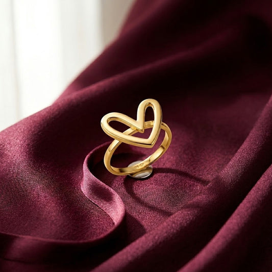 Dainty gold-plated ring with a modern open heart silhouette design, displayed on rich burgundy satin fabric.